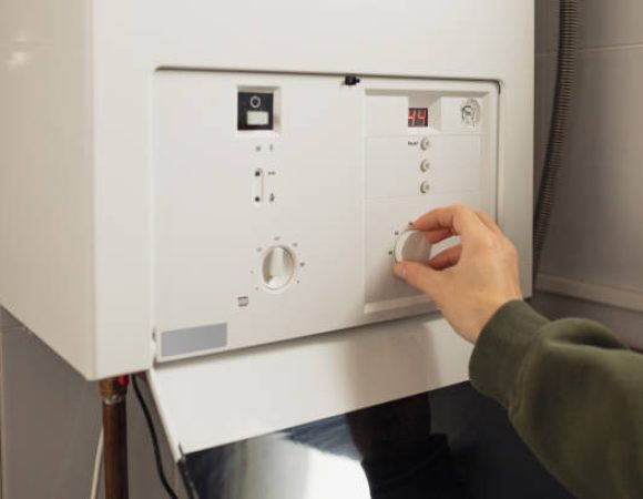 A woman reduces the power of the gas boiler in her home due to an energy crisis A woman reduces the power of the gas boiler in her home due to an energy crisis